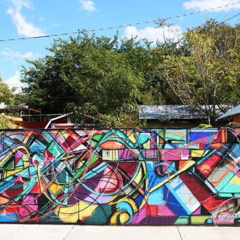 Crazy and colorful photo of a mural that has been spraypainted on a freestanding wall.