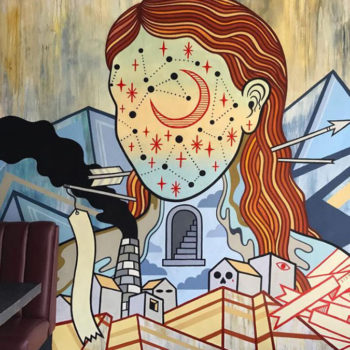 Very cool mural inside a resturant of a womans head with the moon and stars inside of it. It feels like summer or the desert sun.