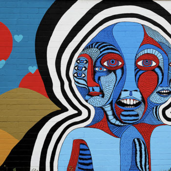 Photo of mural that looks like something out of a cold bad dream of a head with many faces and waves emmiting out of it.