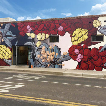Photo of the muraists large botanical painting on the side of a building.