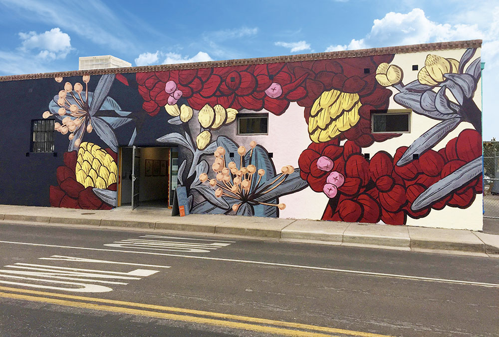 Photo of the muraists large botanical painting on the side of a building.