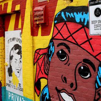 Close up photo of a colorful comic inspired mural that has a young indian boy painted on it in the style of superman.