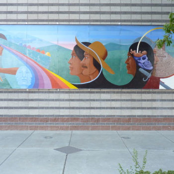 A dated mural of people in a field and a rainbow. made of ceramic tiles.