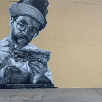 black and white mural of man painting model train