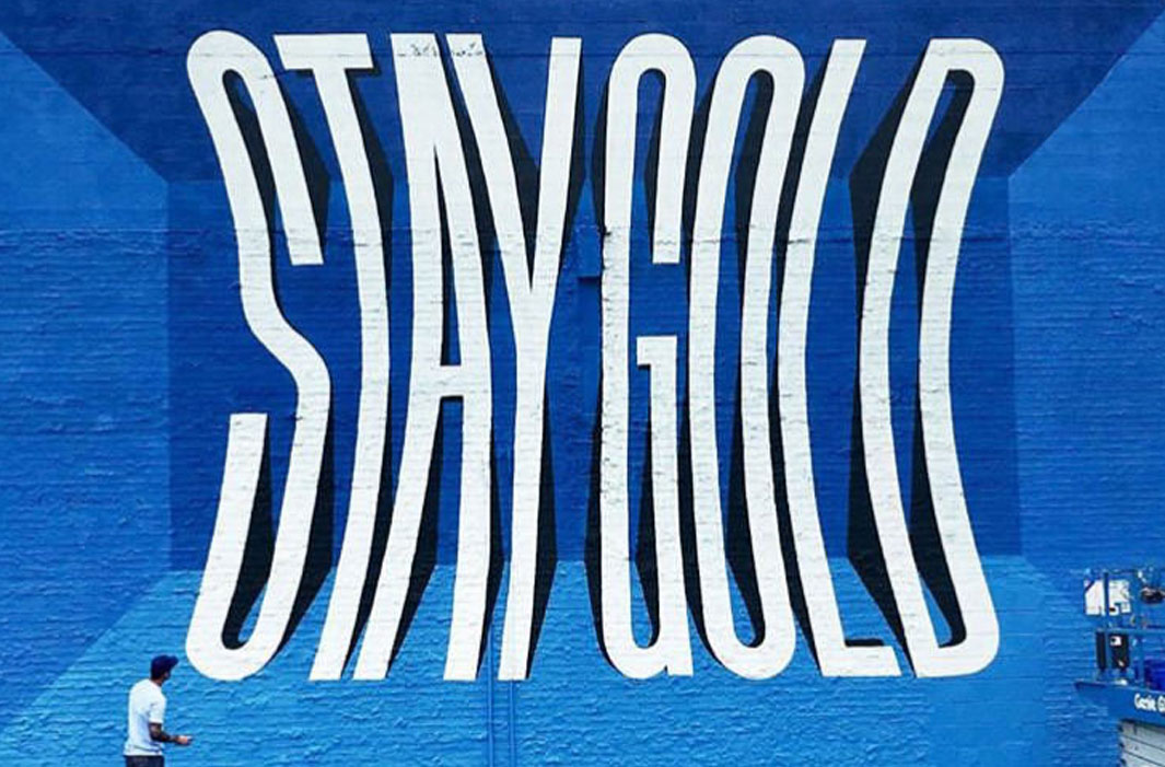 mural of fish-eyed letters reading stay gold